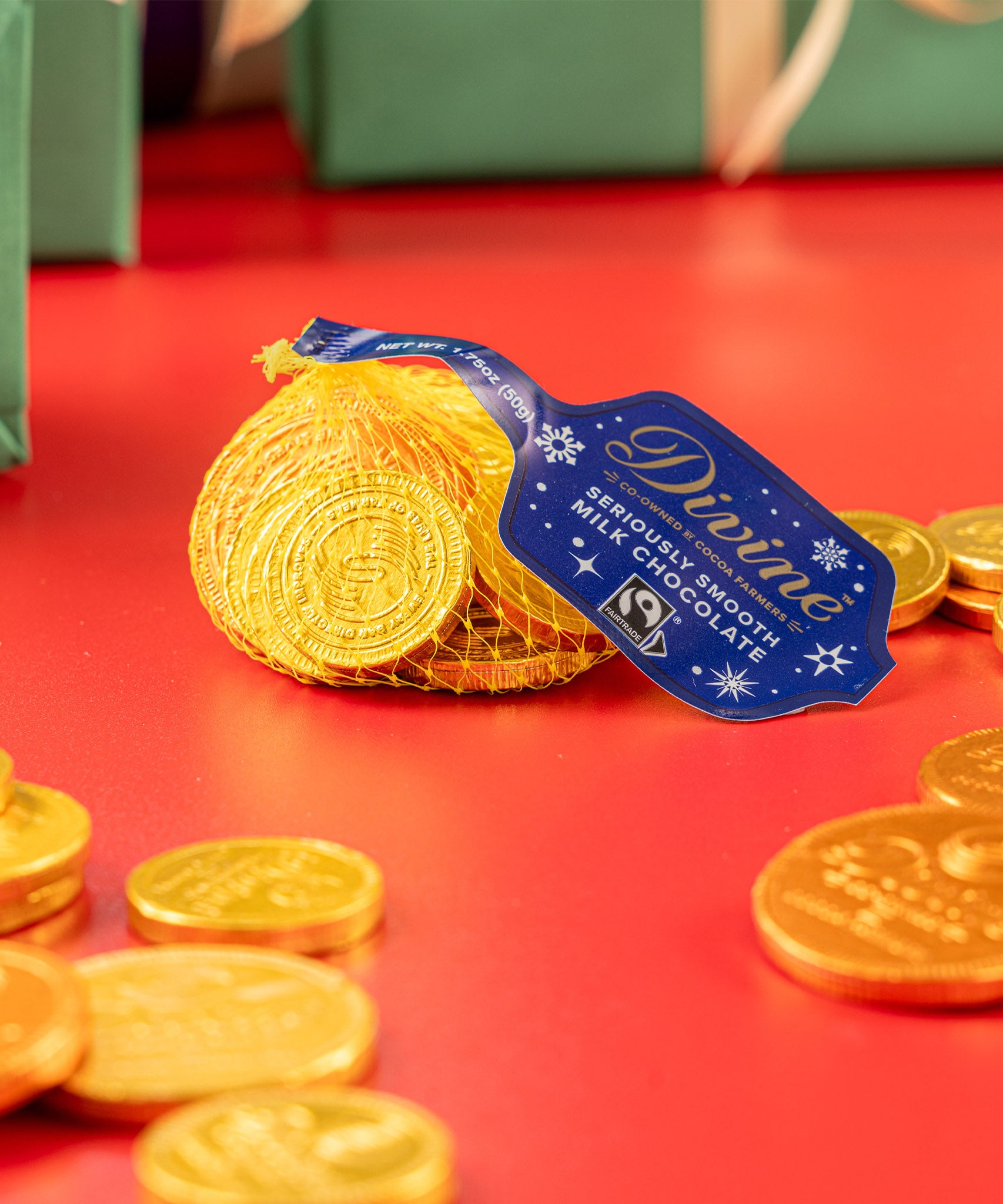 Divine fairtrade milk chocolate coins inside the yellow netted bag with other different sized coins scatted. Chocolate coins available at Babipur.