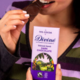 Woman holding a Diving fairtrade 70% dark chocolate bar and eating a piece.