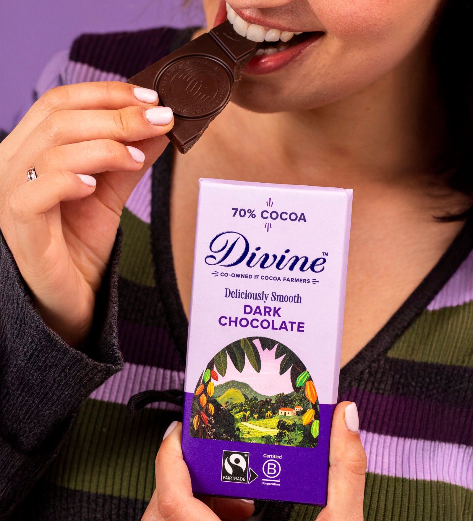 Woman holding a Diving fairtrade 70% dark chocolate bar and eating a piece.