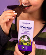 Woman holding a Diving fairtrade 70% dark chocolate bar and eating a piece.