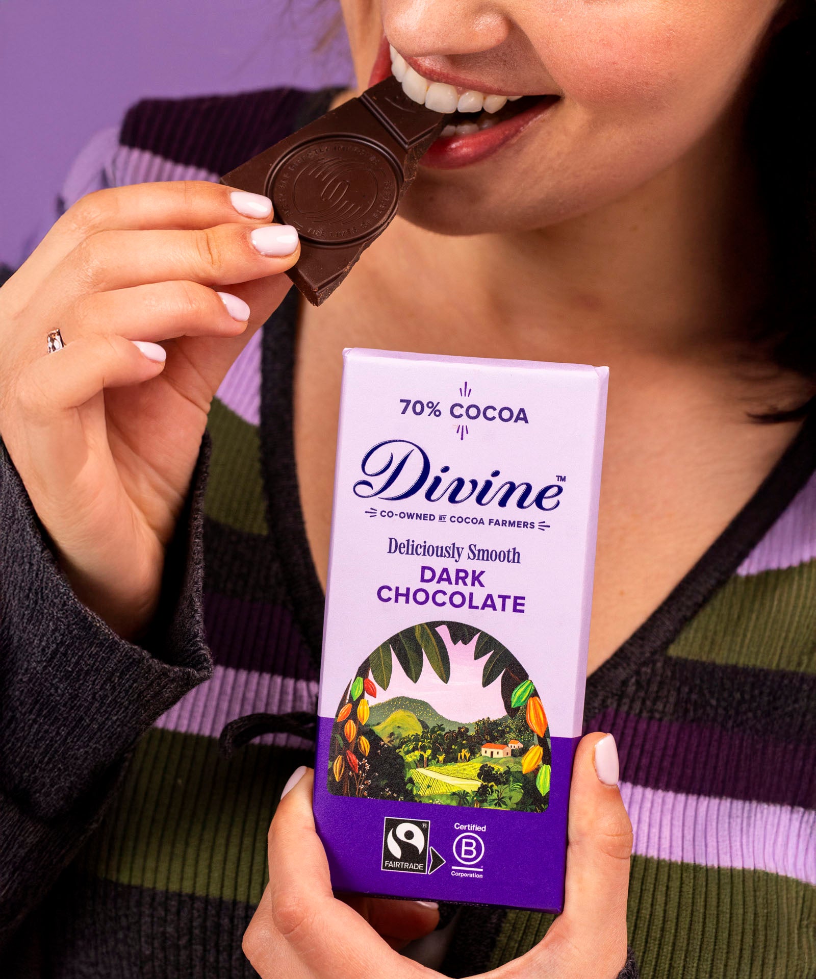 Woman holding a Diving fairtrade 70% dark chocolate bar and eating a piece.