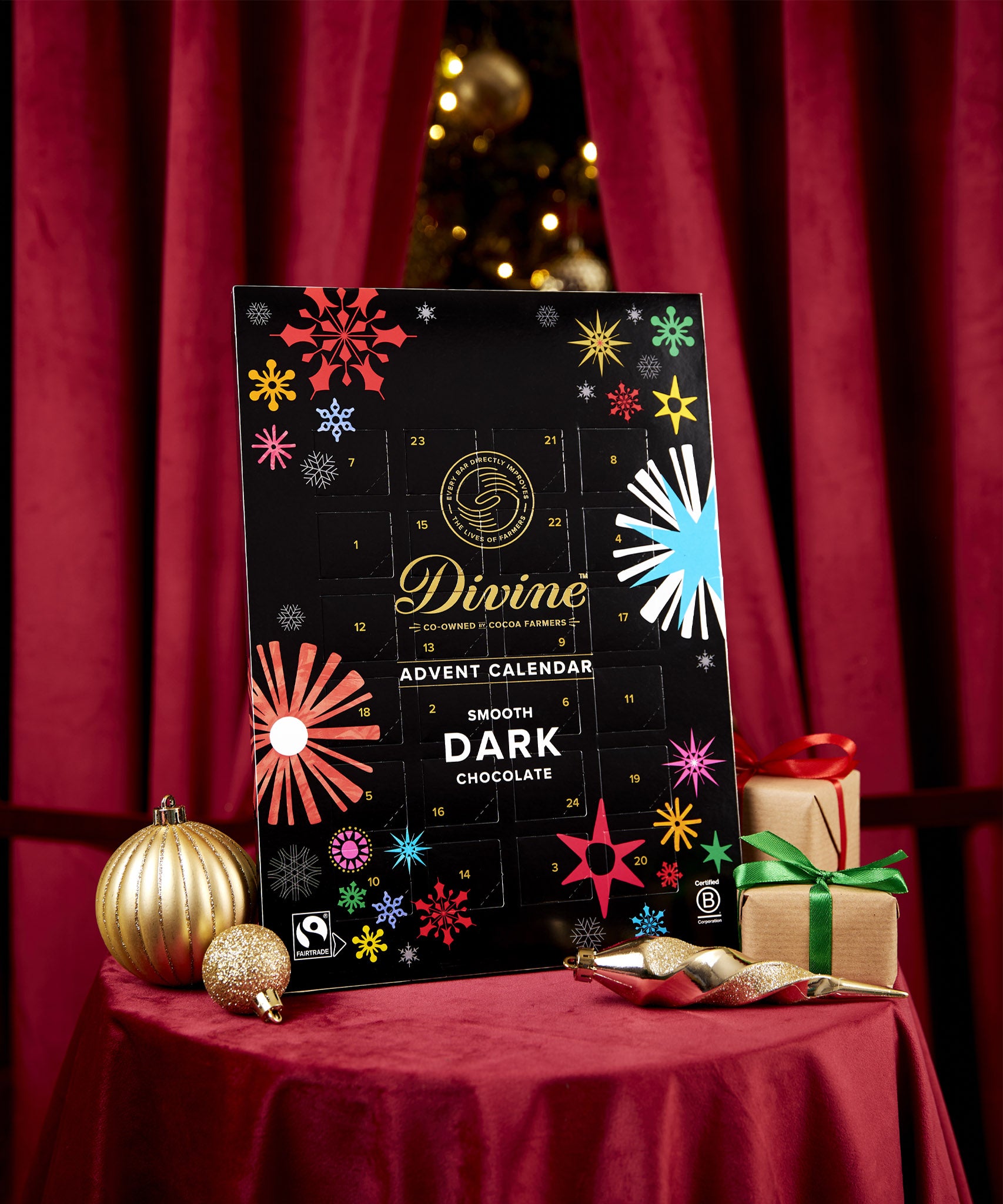 Divine fairtrade milk chocolate advent calendar available at Babipur. Showing the front of the calendar. Calendar is displayed with festive decorations.