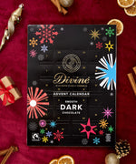 A flatlay with the Divine fairtrade dark chocolate advent calendar laid next to festive decorations. Calendar available at Babipur  