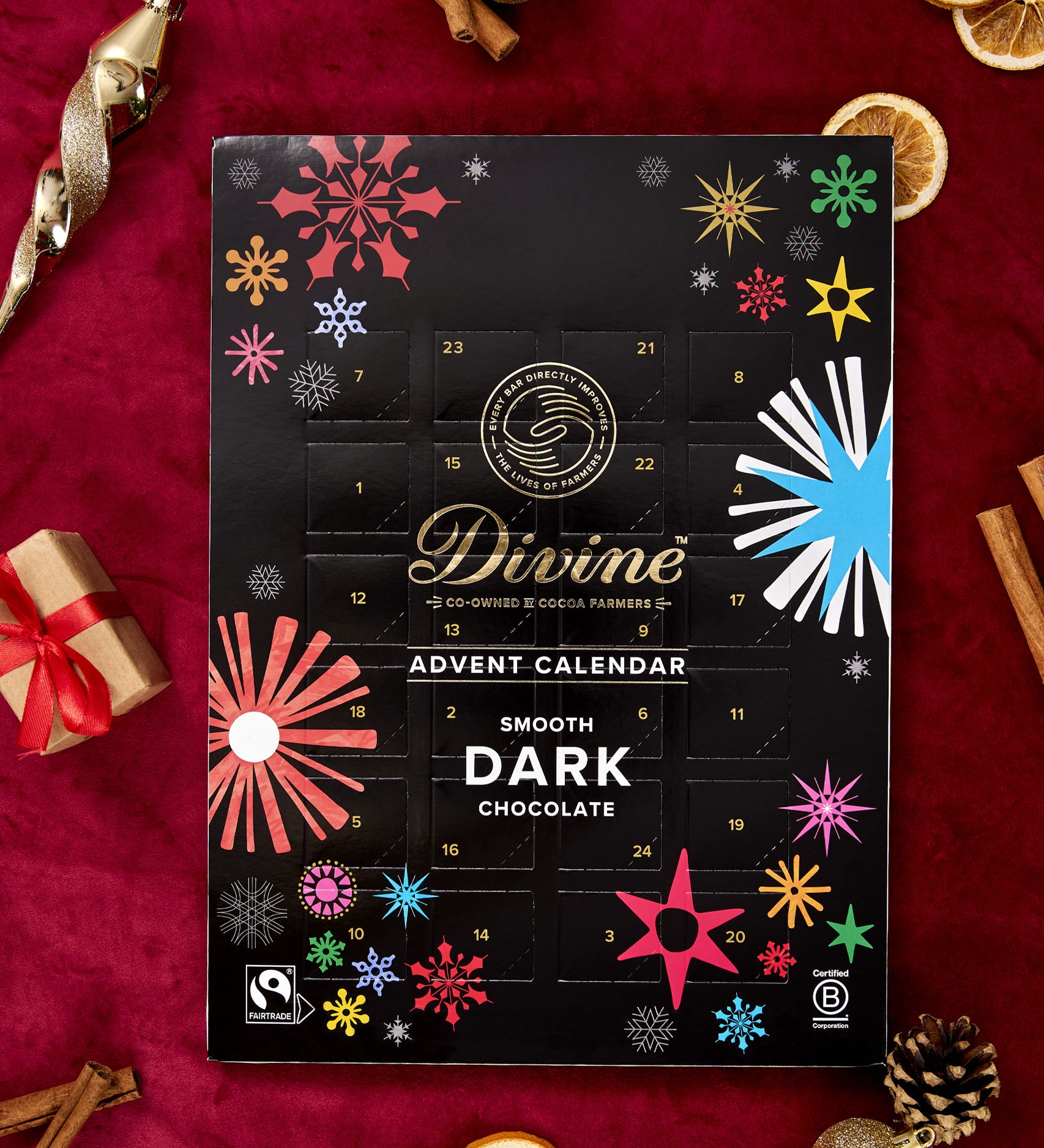 A flatlay with the Divine fairtrade dark chocolate advent calendar laid next to festive decorations. Calendar available at Babipur  