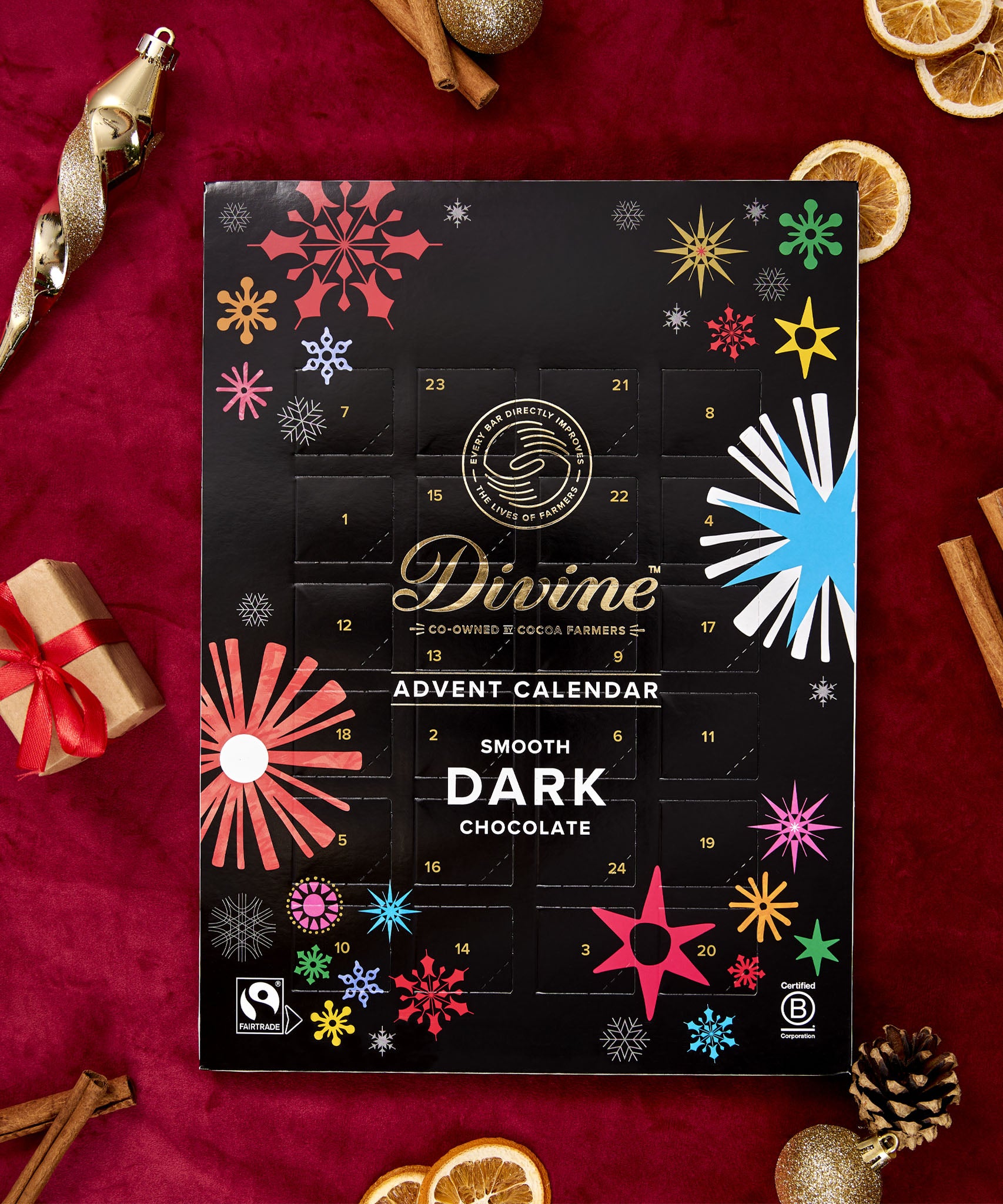 A flatlay with the Divine fairtrade dark chocolate advent calendar laid next to festive decorations. Calendar available at Babipur  