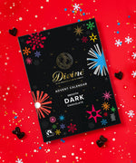 Divine fairtrade milk chocolate advent calendar available at Babipur. Showing the festive inspired design on the front with a red festive background.