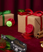 A stack of red Divine fairtrade dark chocolate coins against a Christmas present. Coins available at Babipur.