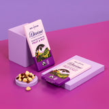 2 bard of Divine fairtrade smooth dark chocolate bar with fruit and nut resting on purple blocks with loose nuts and raisins
