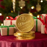 A stack of Divine fairtrade giant milk chocolate coins available at Babipur displayed with festive decorations on a red velvet table cloth