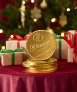 A stack of Divine fairtrade giant milk chocolate coins available at Babipur displayed with festive decorations on a red velvet table cloth