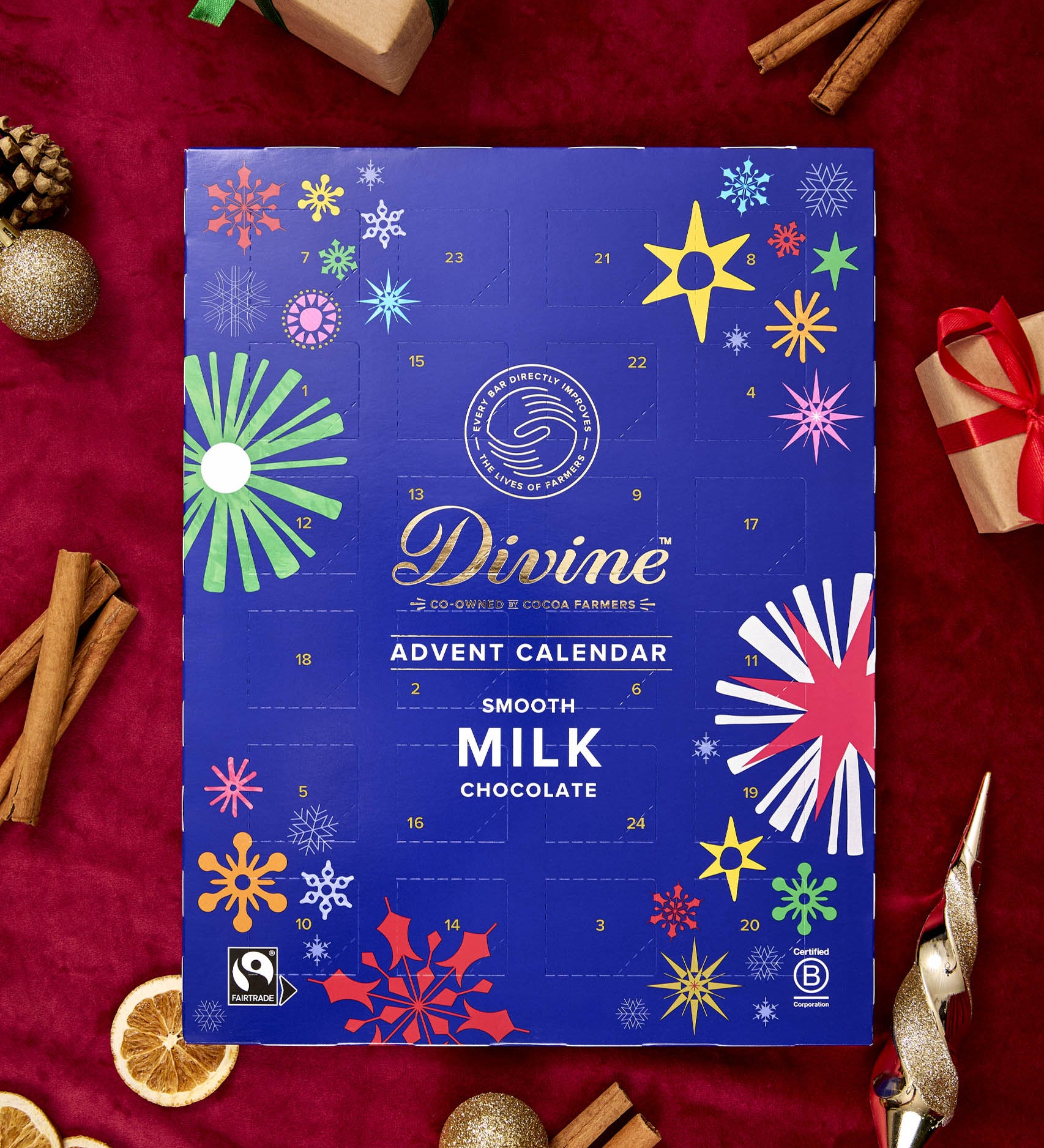 A flatlay with the Divine fairtrade milk chocolate advent calendar laid next to festive decorations. Calendar available at Babipur  