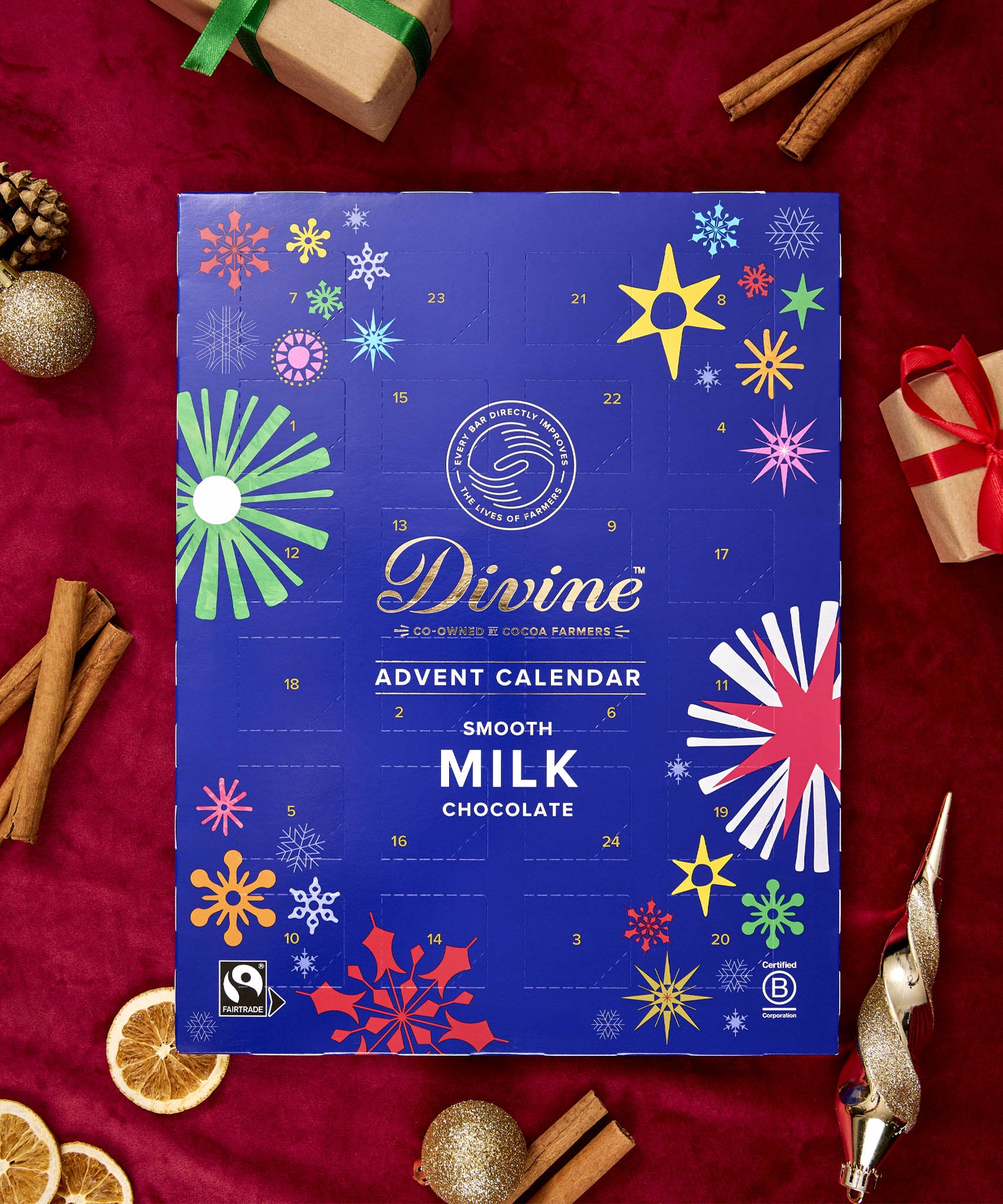 A flatlay with the Divine fairtrade milk chocolate advent calendar laid next to festive decorations. Calendar available at Babipur  