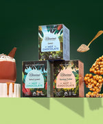 All three Divine fairtrade hot chocolate  boxes displayed on a green platform, shows a golden spoon and a mug of hot chocolate