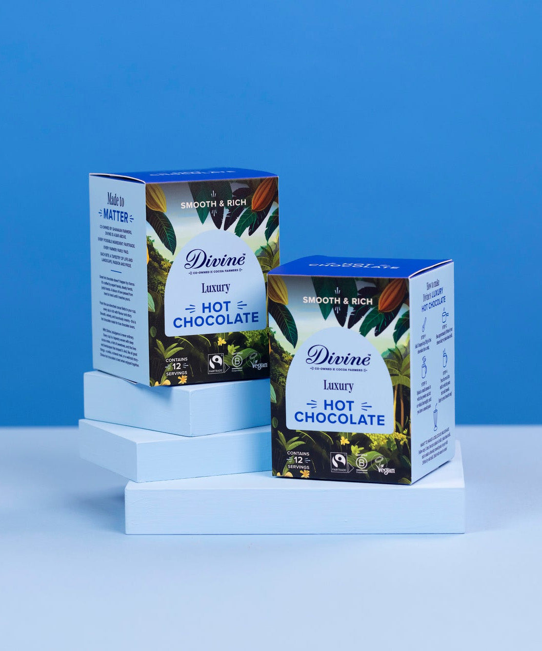 2 boxes of Divine fairtrade luxury hot chocolate boxes standing on a light blue platform