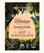 Front of Divine fairtrade luxury hot chocolate with hazelnut praline box shows a illustration of a cocoa farm