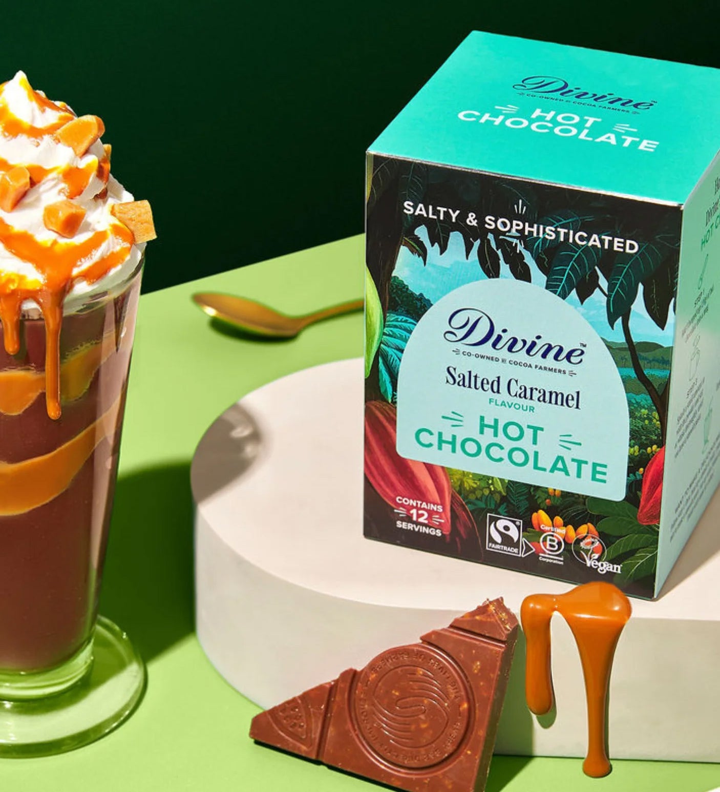 Divine fairtrade salted caramel flavour hot chocolate box standing on a white platform next to a tall glass