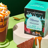 Divine fairtrade salted caramel flavour hot chocolate box standing on a white platform next to a tall glass