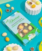 Divine Fairtrade milk chocolate mini eggs with hazelnut praline displayed in a decorated blue and green box lying flat on a blue surface