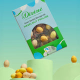 Divine Fairtrade milk chocolate mini eggs with hazelnut praline displayed in a decorated blue and green box balancing on a green platform 