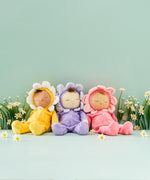 A group of Dozy Dinkum Dolls - Fuchsia Twinkle, Buttercup Pip, Lavender Pickle by Olli Ella, a small baby doll dressed in a pink, purple and yellow velour outfits and flower hood, sold at Babipur.
