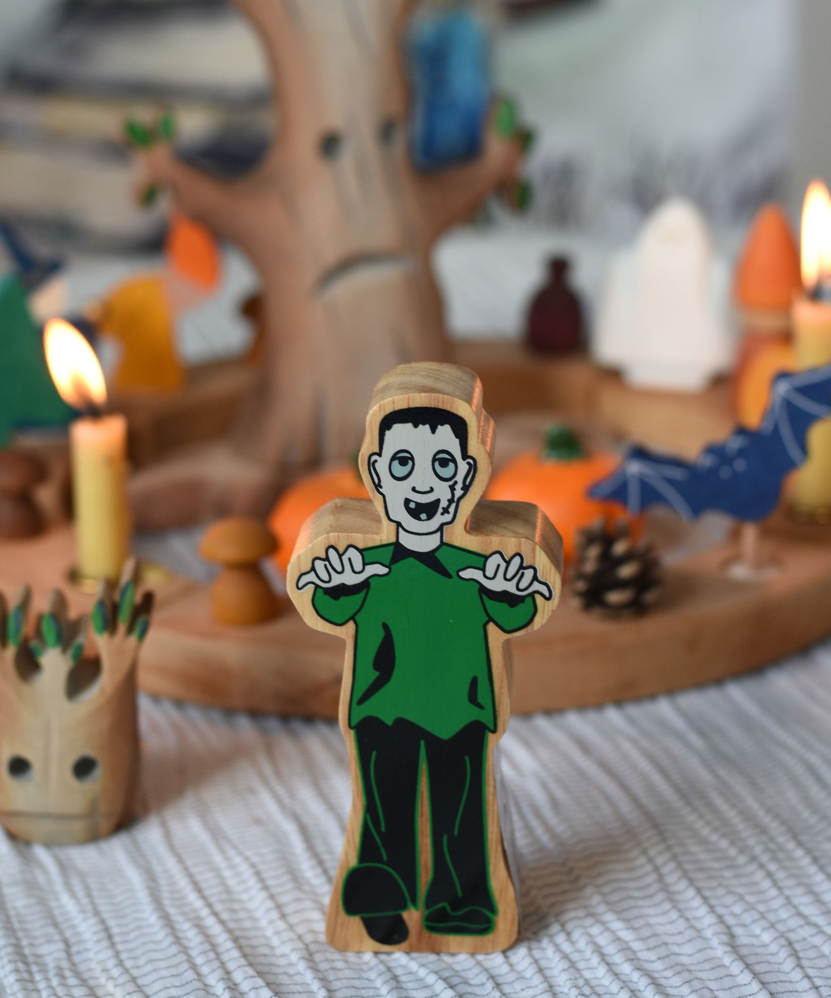 A Lanka Kade green and black Frankenstein style monster wooden figure placed in front of a Halloween themed Grimm's celebration ring set up. 
