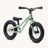Early Rider Charger Balance Bike - Sage Green has a light sage green, low slung frame with chunky black wheels, a black seat and black handle bars. The bike is on a cream background