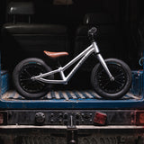 The Early Rider Charger Balance Bike - Violet Haze is stood inside the back of a blue van. The van is muddy which represents the hardiness of the Early Rider bikes