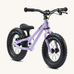 The Early Rider Big Foot Balance Bike - Violet Haze is stood at a slight angle. It has a Violet frame, black wheels, a black seat and black handle bars. The image is on a cream background