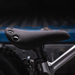 A closer look at the adjustable seat on the Early Rider Big Foot Balance Bike. It is a black seat with flat, black studs on the back of the seat