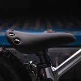 A closer look at the adjustable seat on the Early Rider Big Foot Balance Bike. It is a black seat with flat, black studs on the back of the seat