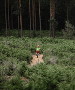 Child riding a bike through a path, with the dark forest in the background