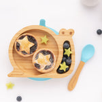 The Blue Eco Rascals Snail plate and spoon. The snail plate contains fruit tarts and various fruit 