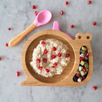 The Pink Eco Rascals snail plate and spoon, with various food in the plate compartments