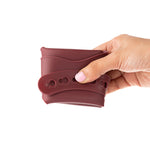 Eco Rascals Silicone Baby Bib in burgundy, folded up in adults hand. 