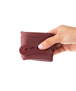Eco Rascals Silicone Baby Bib in burgundy, folded up in adults hand. 