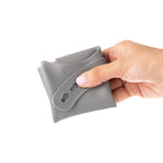 Eco Rascals Silicone Baby Bib in silver grey, folded up in adults hand. 