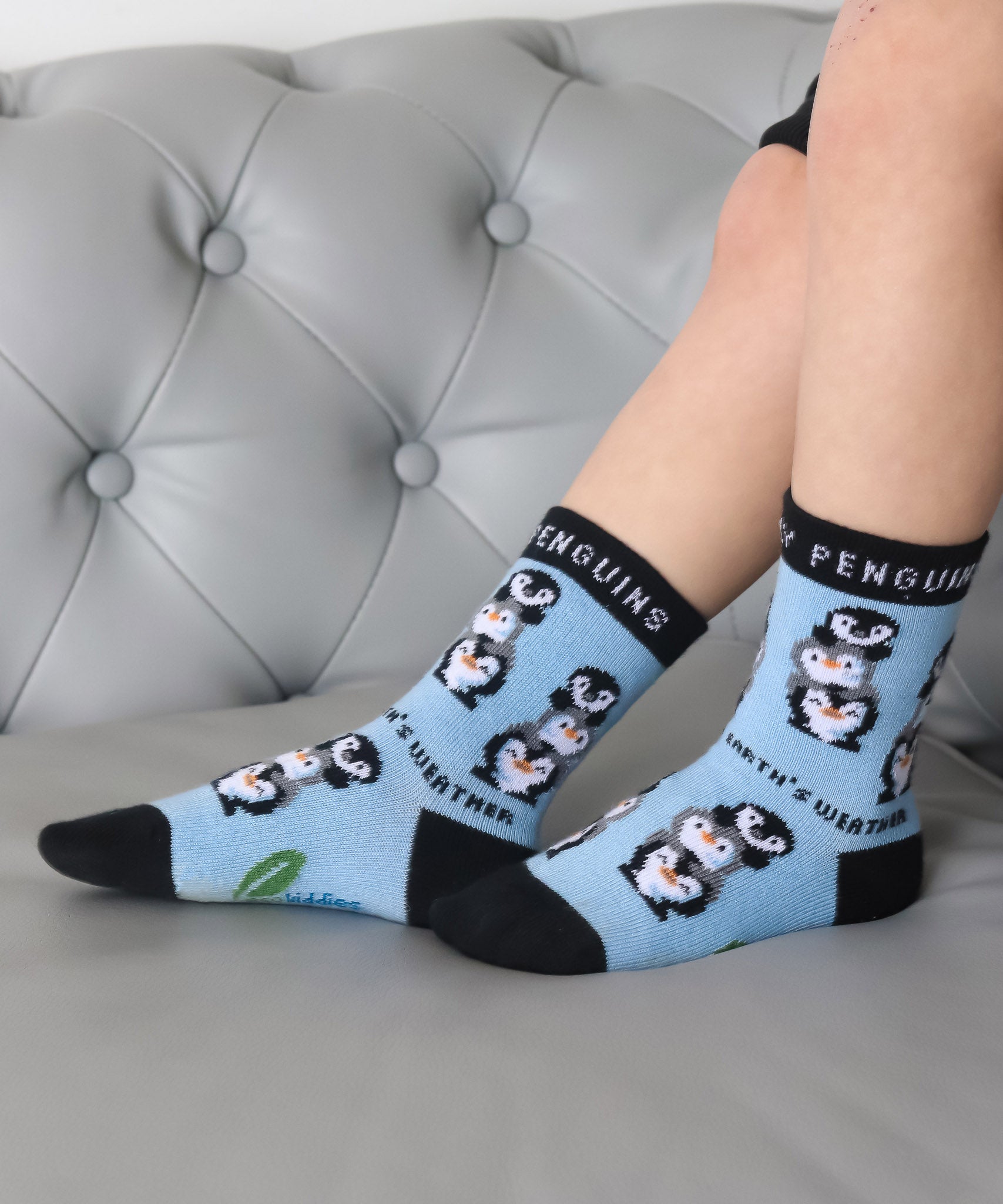 A close up of a child wearing the Eco kiddies organic cotton friendly penguins socks showing the cute playful penguin design detail and branding on the sole 
