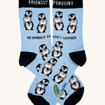 Eco kiddies friendly penguins organic cotton kids socks. A light blue sock with black trim and features cute playful penguins with a slogan saying 'we embrace earth's weather' 