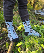A child standing on branches and wearing the Eco kiddies organic cotton friendly penguins light blue socks 