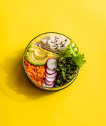 A top down image of the medium Elephant box lunch bowl available at Babaipur. Bowl on a bright yellow background with the lids off and full of different healthy foods. 