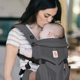 Mother carrying baby in a charcoal grey Ergobaby omni 360 cool air mesh baby carrier and kissing baby's head