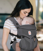 Mother carrying baby in a charcoal grey Ergobaby omni 360 cool air mesh baby carrier and kissing baby's head