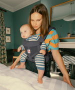 Mother carrying baby in the Ergobaby charcoal grey omni 360 air mesh carrier in the bedroom 