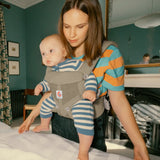 Mother carrying baby in the Ergobaby soft olive green omni 360 air mesh carrier in the bedroom 
