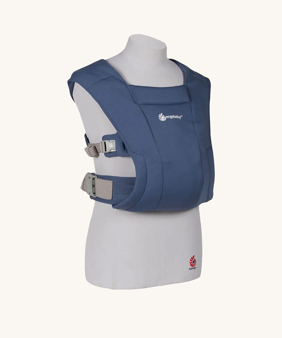 The Ergobaby Soft & Snug knit newborn baby carrier in a soft navy colour, from a side angle view.
