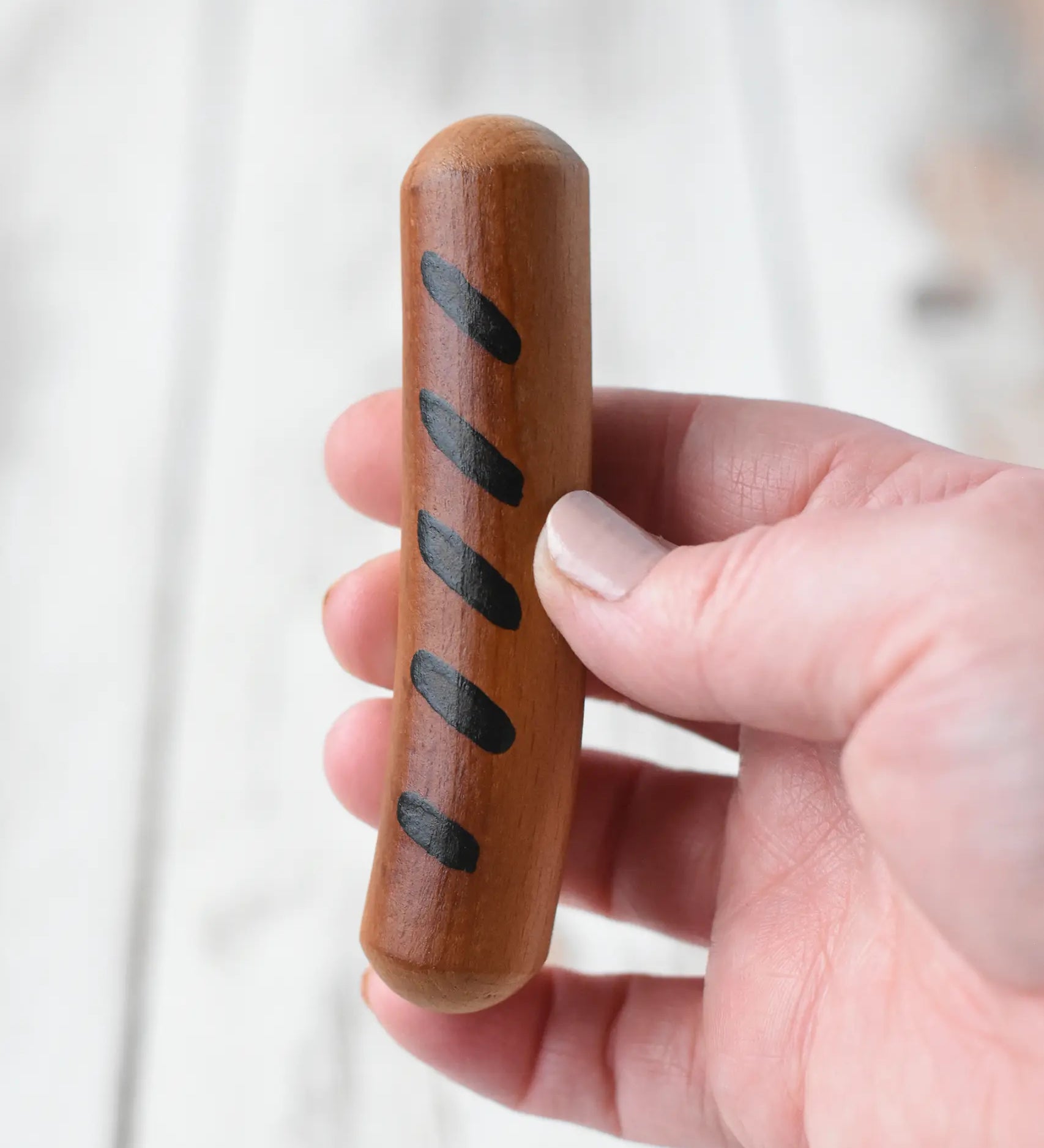 Erzi Frying Sausage Wooden Play Food in an adult's hand. Cooked toy sausage with grill marks.