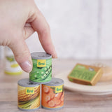 Erzi Tinned Vegetables (carrots, peas, sweetcorn), wooden canned veggie play food, stacked in a play set up with a hand for scale.