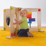 A child playing with the Erzi Baby Guitar Wall Board, which is connected to other Erzi Toy Wall Board activities
