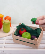 A hand holding a small wooden broccoli toy by Erzi, perfect for a play kitchen, sold at Babipur.