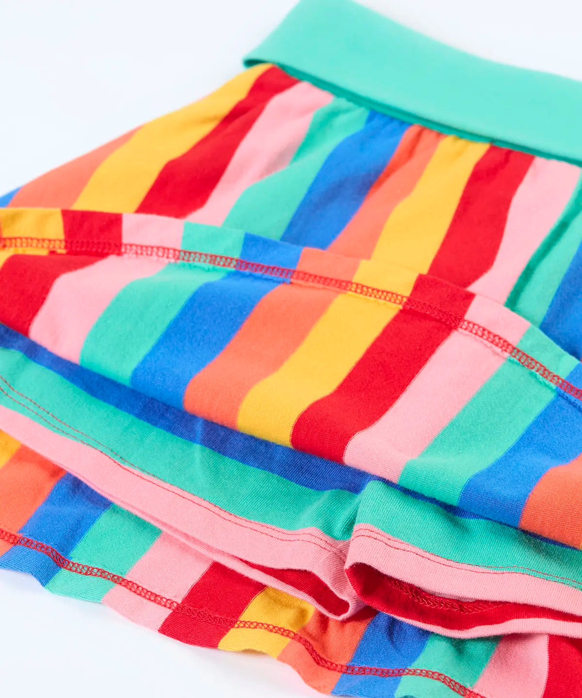 Frugi Alba skort in rainbow stripes with a mint green waistband laid flat showing the shorts underneath